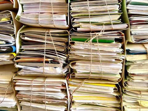 A close-up shot of heavy stacks of old, untidy paper documents, folders, and archives tightly bound together with twine, conveying bureaucracy and historical records