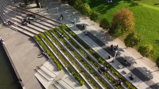 People relaxing on riverside steps with green terraces in Wrocław, Poland