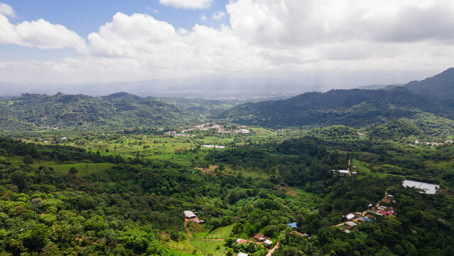 Aerial view of the mountainous landscape of Comayagua, Honduras, with green hills, scattered homes, valleys and forest under a bright tropical sky.