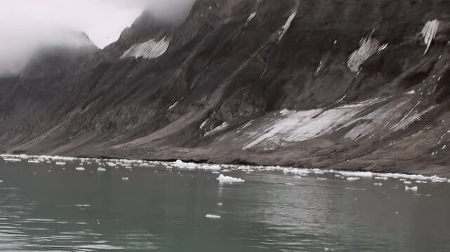 Rugged mountains rise above cold water scattered with floating ice. Visible details include wide framing, while the wider composition emphasizes natural texture and depth.