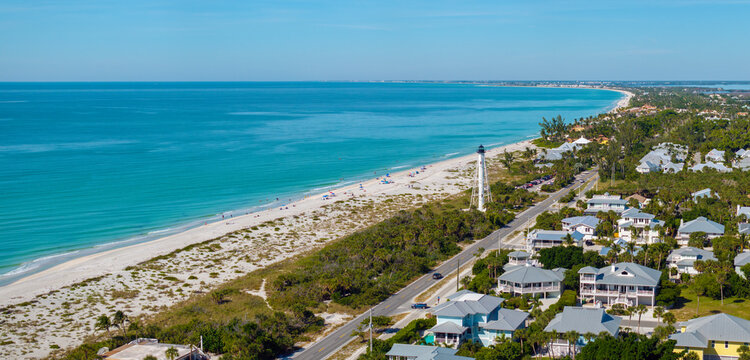 Expensive waterfront houses and white Boca Grande lighthouse on ocean shore. Small town on Gasparilla Island in southwest Florida. Premium housing development in the USA