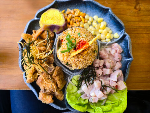 Peruvian dish with chaufa rice, fish chicharron, ceviche, choclo corn, cancha and sweet potato seen from above