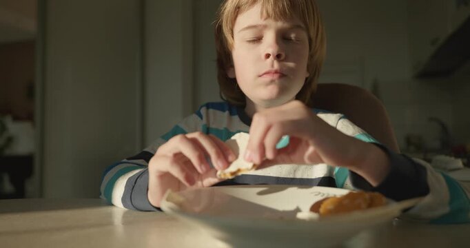 Close-up kid boy eats breakfast lunch in kitchen. 4K 10-bit