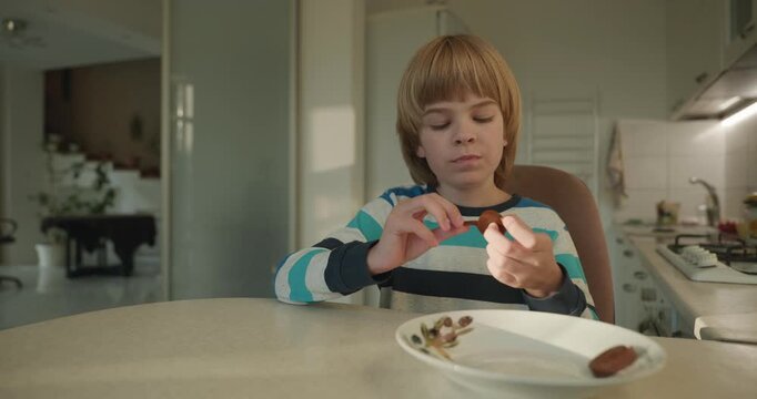 Close-up kid boy eats breakfast lunch in kitchen. 4K 10-bit