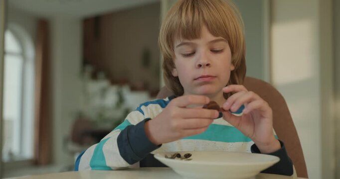 Close-up kid boy eats breakfast lunch in kitchen. 4K 10-bit