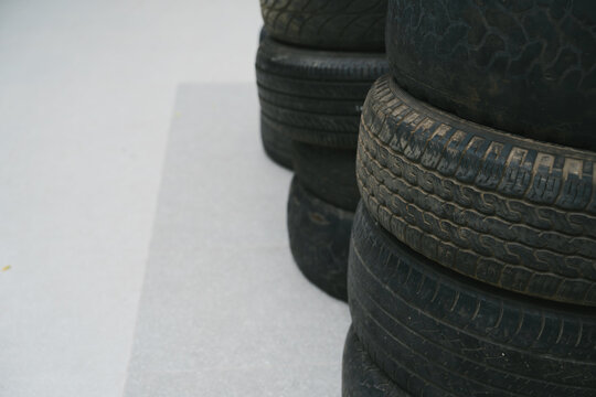 Used black tire stack showing abandoned worn rubber tread creating grim mood while stacked automotive wheel equipment pile up in workshop
