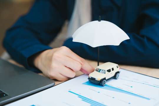 Car insurance protection concept with secure vehicle under white umbrella providing calm feeling while businessman manages policy