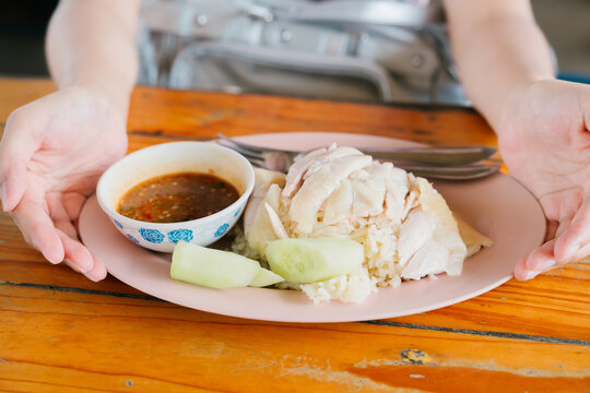 Hainan chicken rice dish steamed meat served with spicy sauce and cucumber slice enjoyed by happy person