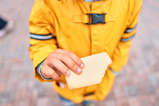 Boy in Yellow Rain Jacket Holding a Cracker Outdoors