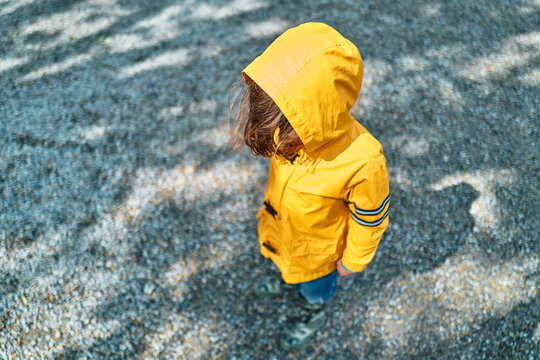 Boy in Yellow Rain Jacket With Hood Up Standing on Gravel