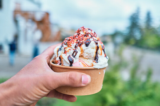 Hand Holding a Paper Cup of Ice Cream Sundae With Sprinkles Outdoors