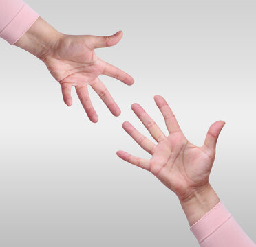 Two outstretched hands reach towards each other in a gesture of help and support against a light background.