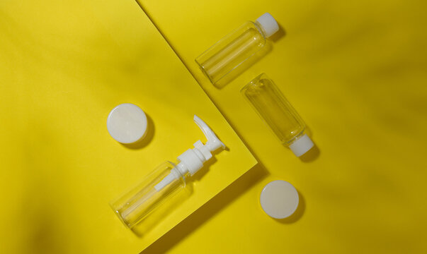 A set of transparent plastic bottles and jars with white lids on a yellow background