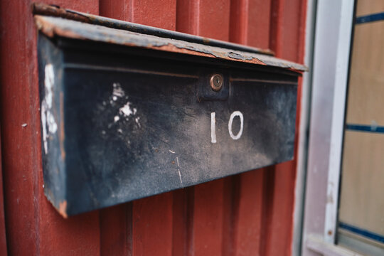 Rustic Black Metal Mailbox With Number 10 on Red Corrugated Siding