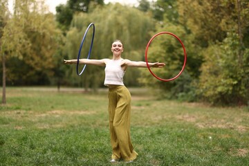 Athletic young woman exercising with hula hoops in park © New Africa
