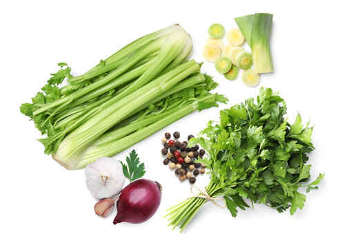 Celery stalks, parsley, onions, garlic and peppercorns on white background, top view