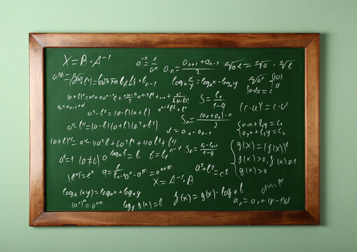 Chalkboard covered with mathematical equations on pastel green wall