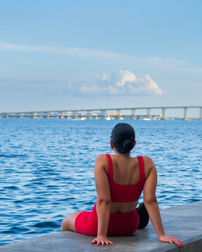 Woman Sitting by the Waterfront Looking at the Ocean and Bridge