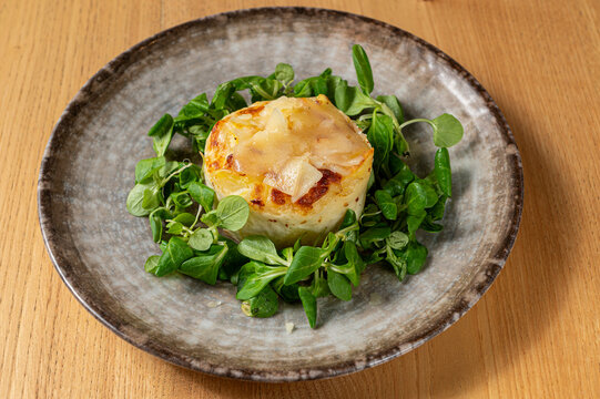 Baked potato timbale with a golden crust served with fresh lamb's lettuce on a rustic ceramic plate