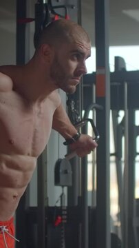 Focused athlete performing intense cable workout for chest and arm strength, highlighting muscular definition, dedication, and controlled movement in modern gym