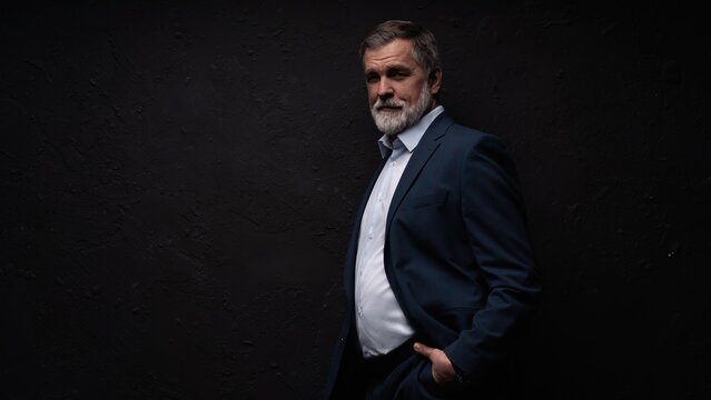 Studio portrait of senior businessman in suit on dark background