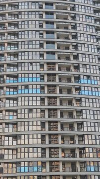 Symmetrical facade of a modern high rise building with many windows and balconies. Urban architectural pattern creating a hypnotic effect