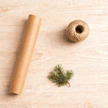 Kraft wrapping paper twine and evergreen on a pale wooden table