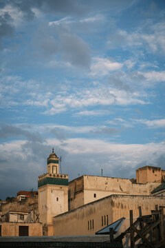 vertical Historic Minaret and Rooftop Skyline Against Cloudy Sky in Fes Morocco 