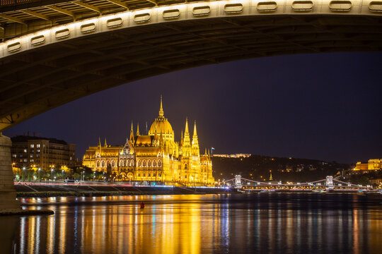 Illuminated Hungarian Parliament framed by Margit Bridge arch at night, Budapest, Hungary