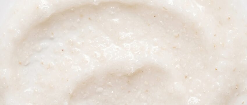 Milky scrub texture with exfoliating particles. Creamy body scrub swatch close up. Natural cosmetic peeling product