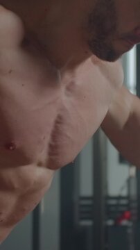 Focused athletic man performing intense cable workout in modern indoor gym environment, highlighting muscular upper body strength, effort, and training determination