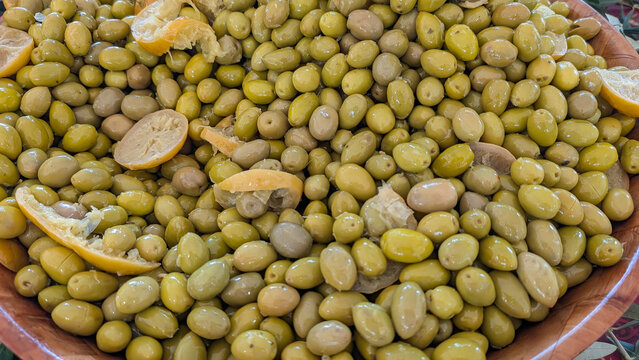 Green olives with lemon pieces displayed at a food market. 