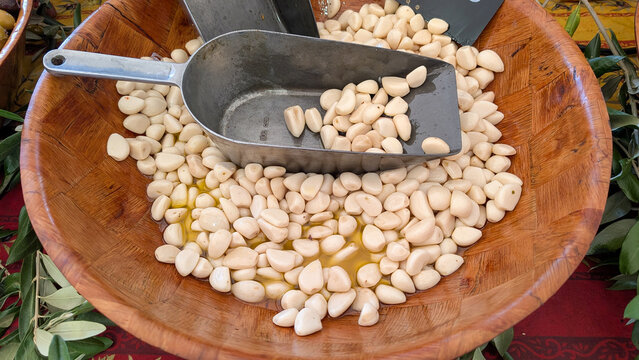 Peeled garlic cloves with metal scoop at a food market. 