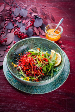 Vegetable vegan salad with red beet, carrots and fresh arugula salad leaves served as close-up in a design bowl