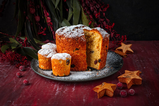 Artisan homemade traditional classic Italian pannetone cake with raisins served as close-up on rustic plate with decoration on wooden table