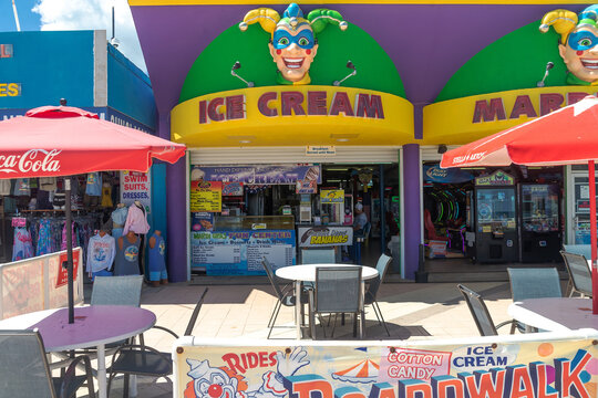 Red branded umbrellas shade tables outside an open Florida ice cream shop.