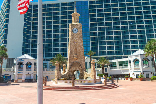 Coquina Clock Tower stands in a paved plaza before a Daytona hotel.