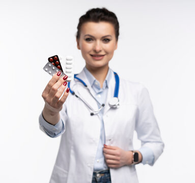 Attractive woman qualified specialist therapist wear white doctor robe hand hold pills isolated on white background.