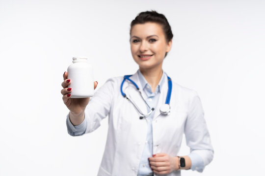Attractive woman qualified specialist therapist wear white doctor robe hand hold pills isolated on white background.