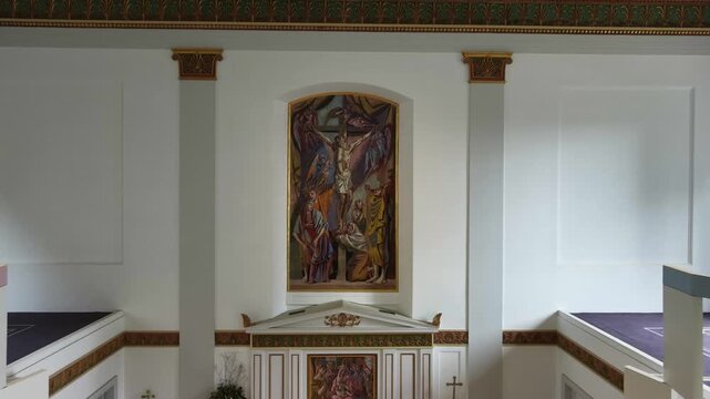Interior of St Johns Waterloo church with a pipe organ, a modern crucifixion painting and a wrought iron chandelier in London