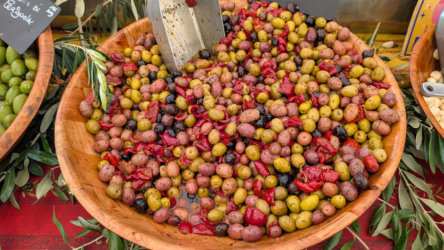 Mixed olives with red peppers and herbs in a wooden bowl. 