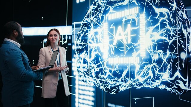 Engineers monitor artificial intelligence and neural network progress on laptop, developing AI and machine learning technology through teamwork.