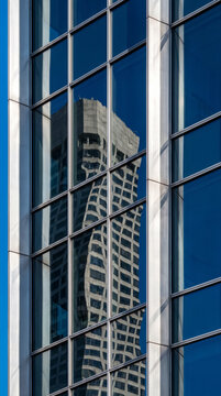 Distorted tower reflection within blue glass curtain wall of downtown office building skyline