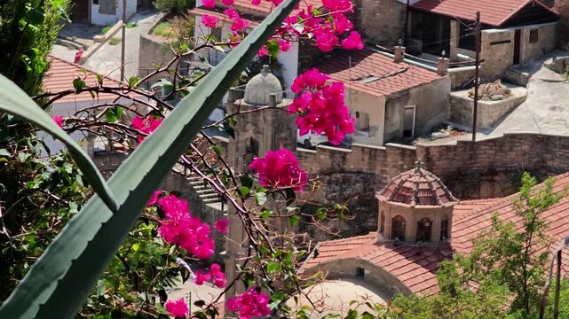 Tochni village in Cyprus with the Holy Church of Saints Constantine and Helen, traditional stone buildings, red tile roofs and vibrant bougainvillea flowers