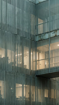 Layered metal mesh facade veiling softly lit offices as concept of transparency and privacy