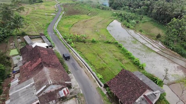 Drone shot of peaceful countryside road and paddy fields in Java