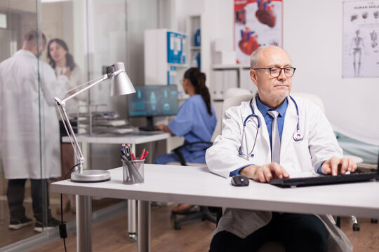 Senior doctor using desktop computer in collaborative clinic office