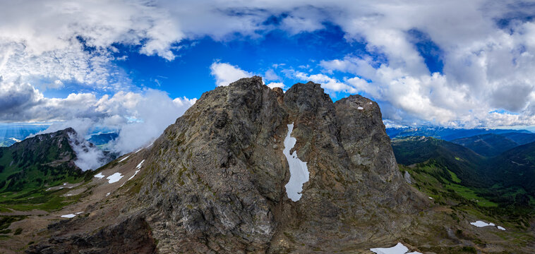 Rugged Mountain Peak With Snow Patch Under Blue Sky and Dramatic Clouds in Chilliwack BC Canada