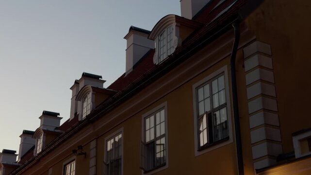 Elegant historic building facade with roof dormers and windows against clear evening sky