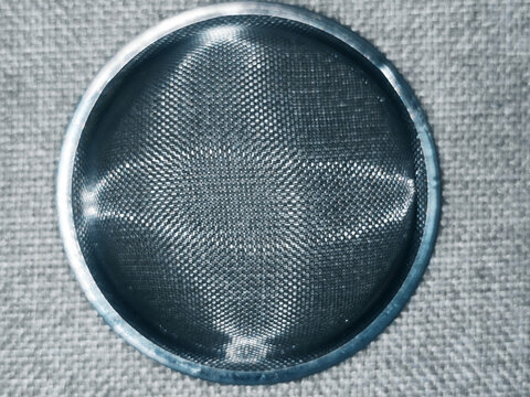 Round metal mesh strainer on a woven fabric surface